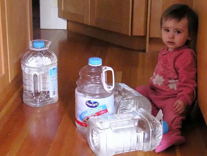 Cute baby playing with empty water jugs that were used when a boil water advisory was issued after a hurricane.