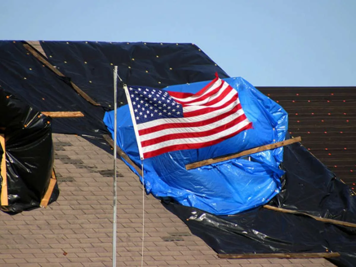 Here's an example of a damaged roof with a temporary blue tarp on it, applied by the homeowner. Public Domain 