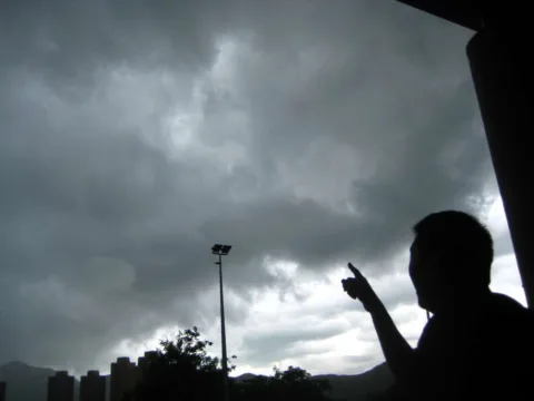 Pointing at storm clouds.