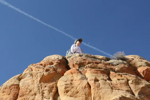 Standing on a cliff below a contrail.